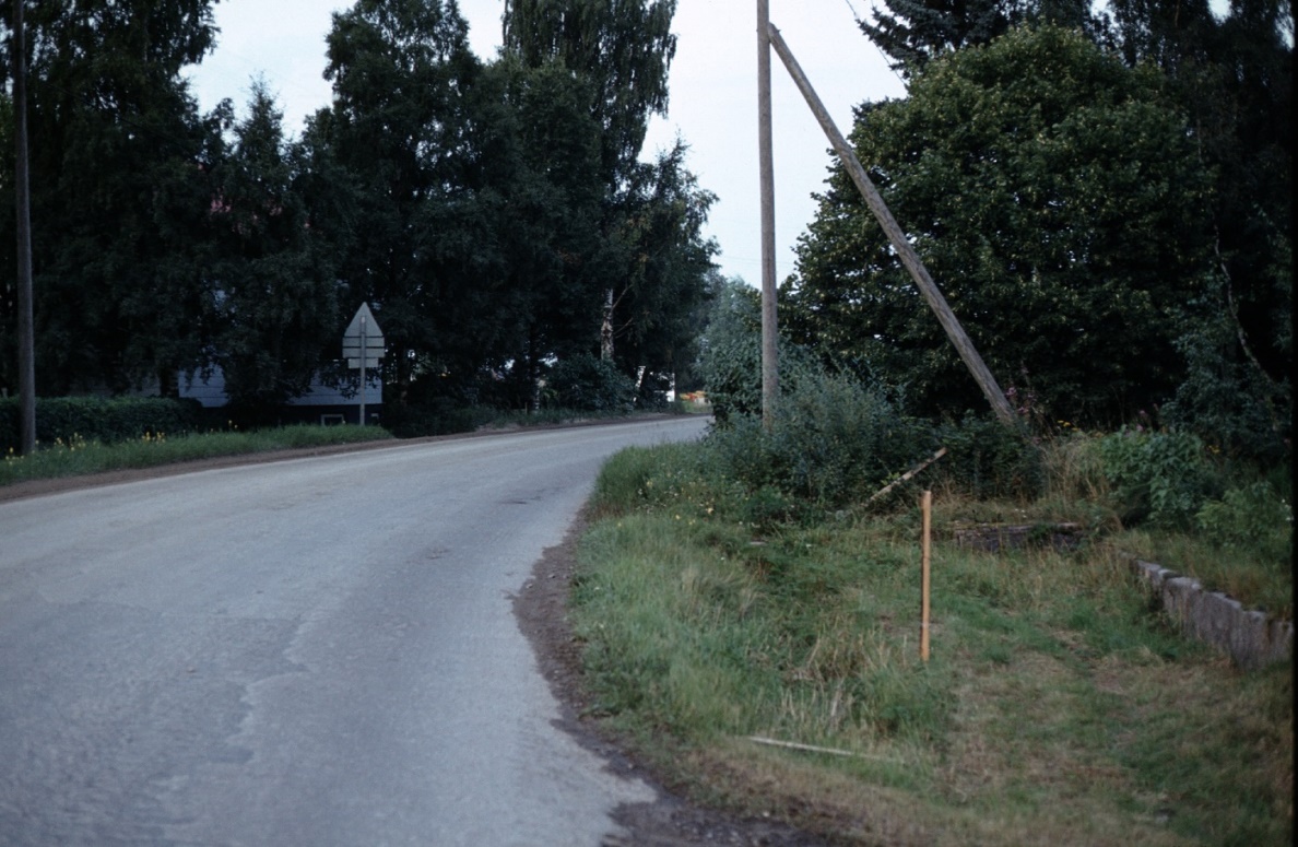 Då Rurik Norén rev ner gården så lämnade han stenfoten kvar, som syns i gräset till höger här på Ingmar Rosengårds foto. På andra sidan vägen skymtar Klåvus gård.