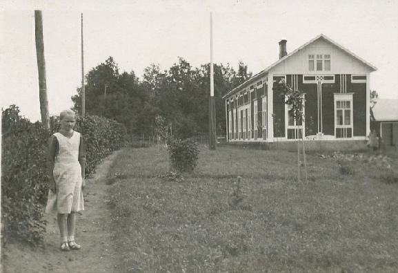 Agnäs gamla gård var en extra dekorativ men i övrigt tidstypisk bondgård. Här står yngsta dottern Verna Agnäs (f. 1925, gift Björkskog, bor i Lappfjärd). 