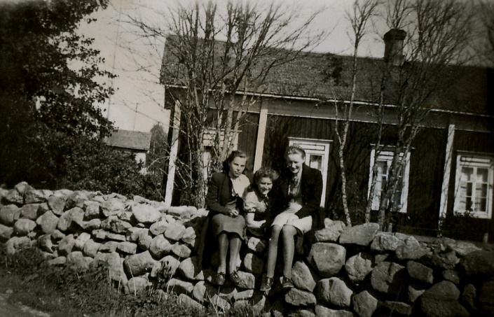 Bakom den vackra stenmuren byggde Agnäs Henrik och Mina sin sytningsstuga där de bodde till sin död. Den stod med gaveln eller kanske hörnet mot landsvägen. På muren sitter fr.v. Alice Gröndahl, Alice Björklund och Gerda Klåvus. 