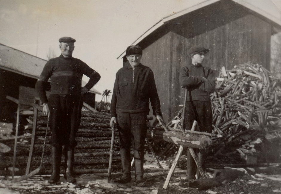 Här på vedbacken står Frans Agnäs med bågsågen, i mitten står hans far Henrik Agnäs och pojken till höger som ser mot folkskolan är Eskil Agnäs.