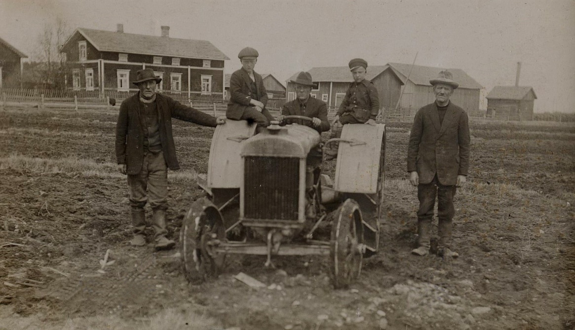 På bilden från 1926 står ”Kaalas-Hindrik” till vänster och J.H. Storkull till höger. Gunnar sitter på traktorn med Einar och Eskil på sidorna. I bakgrunden Krook-Josefs gård före den blev tillbyggd med en vindsvåning. År 1929 skulle ju mejeribyggnaden resa sig på åkern bakom traktorn. 