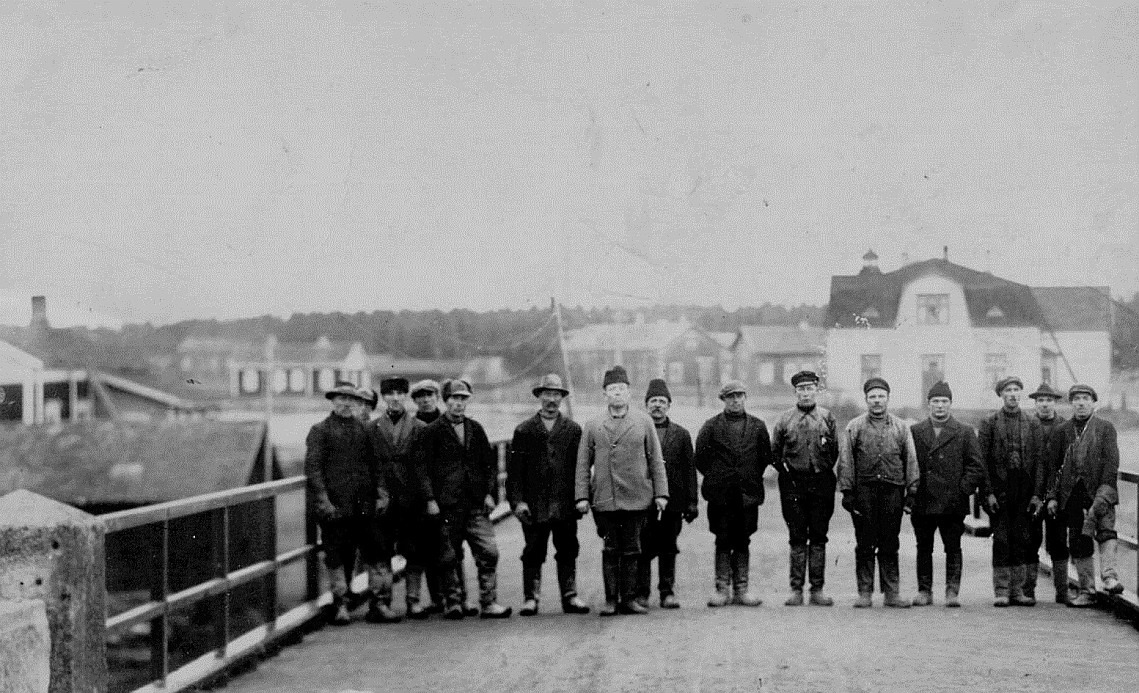 Denna grupp är fotograferad från den södra sidan, längst till vänster Josef Berglund och så finns där Hemming Nyholm, Emil Nyholm, Viktor Eklund, Karl Hemberg och många andra okända. Längst till vänster Vidbergs hus, Algot Rosengårds hus, i mitten Gunnar Långqvists långa bondgård och till höger handlanden Storkulls butik. Bilden från mitten av 1920-talet, möjligtvis 1928 då brolocket förnyades helt.