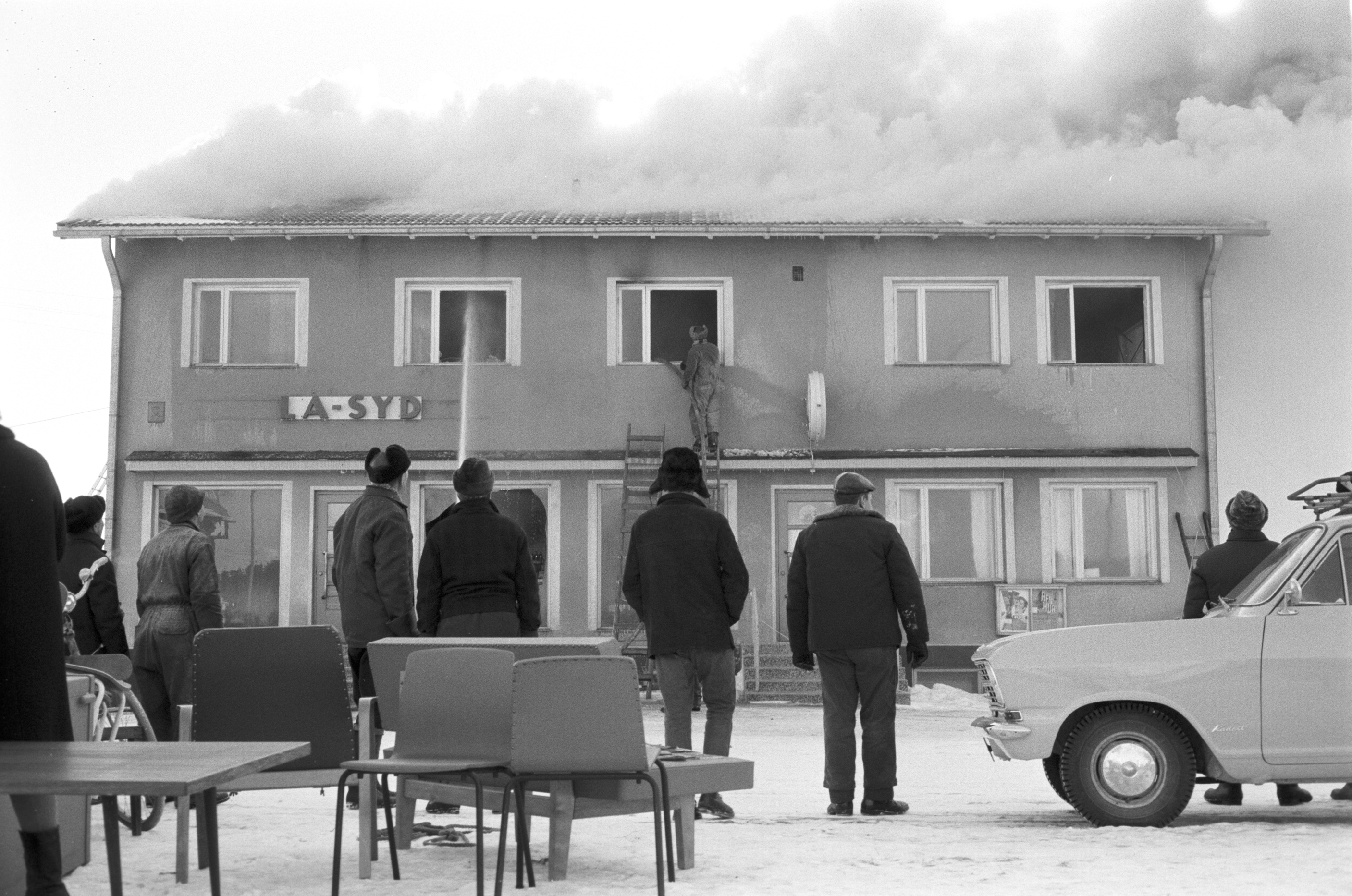 En del av inredningen från Sparbankens kontor kunde räddas medan själva byggnaden förstördes helt. Här står en del bybor och ser på då brandmännen försöker släcka elden.