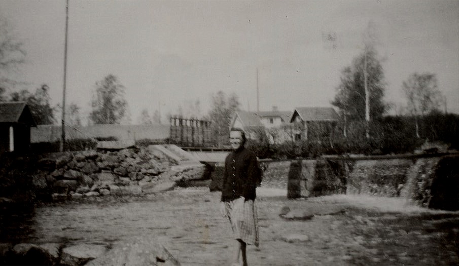 Här står Ellen Ånäs nedanför dammen vid Pärus-Fors. Kvis Olofs gård syns i bakgrunden.