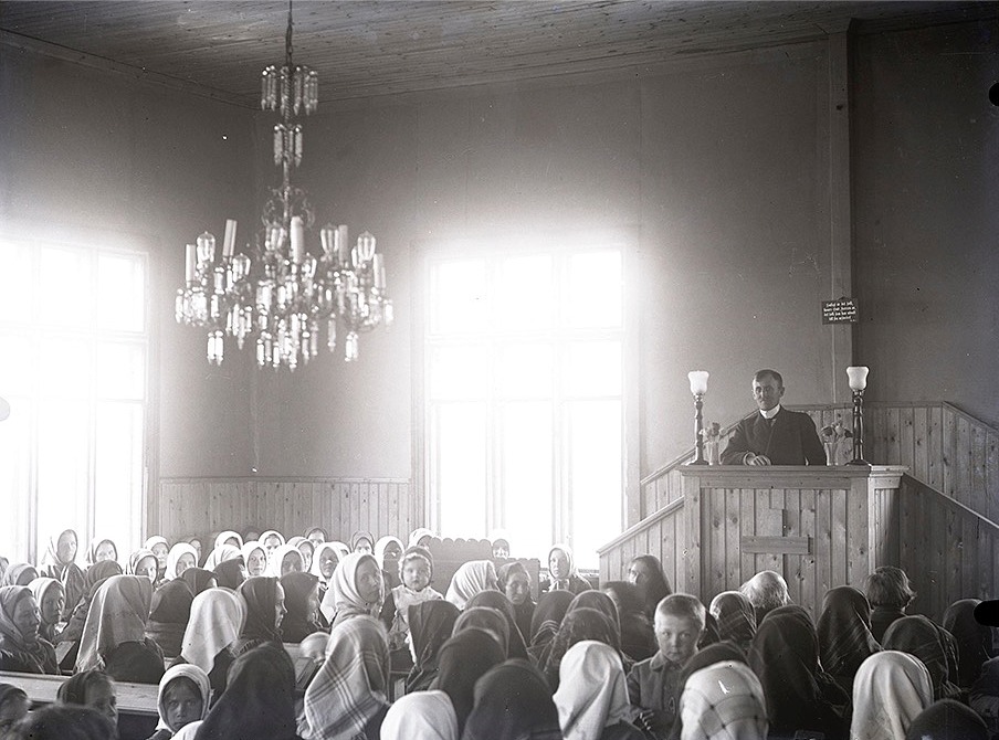 Sågägaren Viktor Nylund var en duktig fotograf och här har han lyckats över förväntan. Han fick med både takkronan, predikanten och en stor del av åhörarna. Ljuset kommer symboliskt vackert in från båda fönstren.