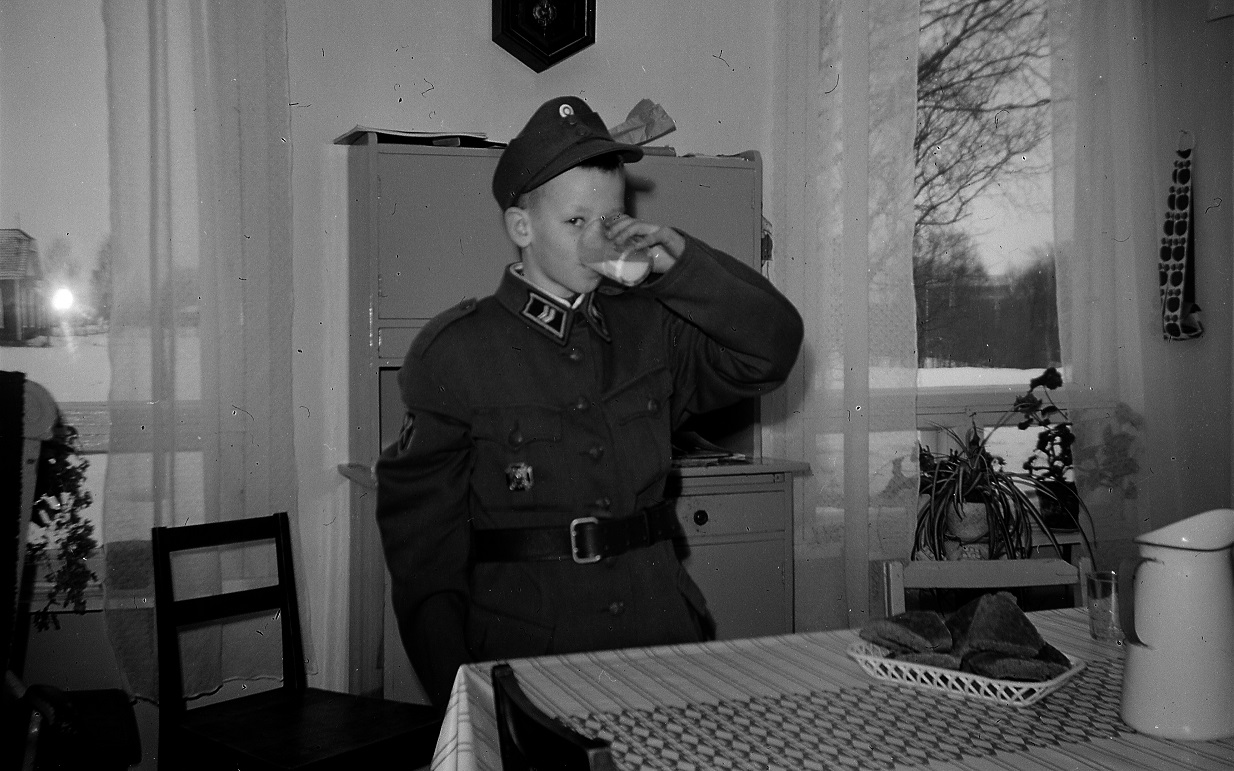 Lasse, 10 år provar storebror Per-Eriks militärkläder år 1966. I det ena köksfönstret syns bönhuset på granntomten.