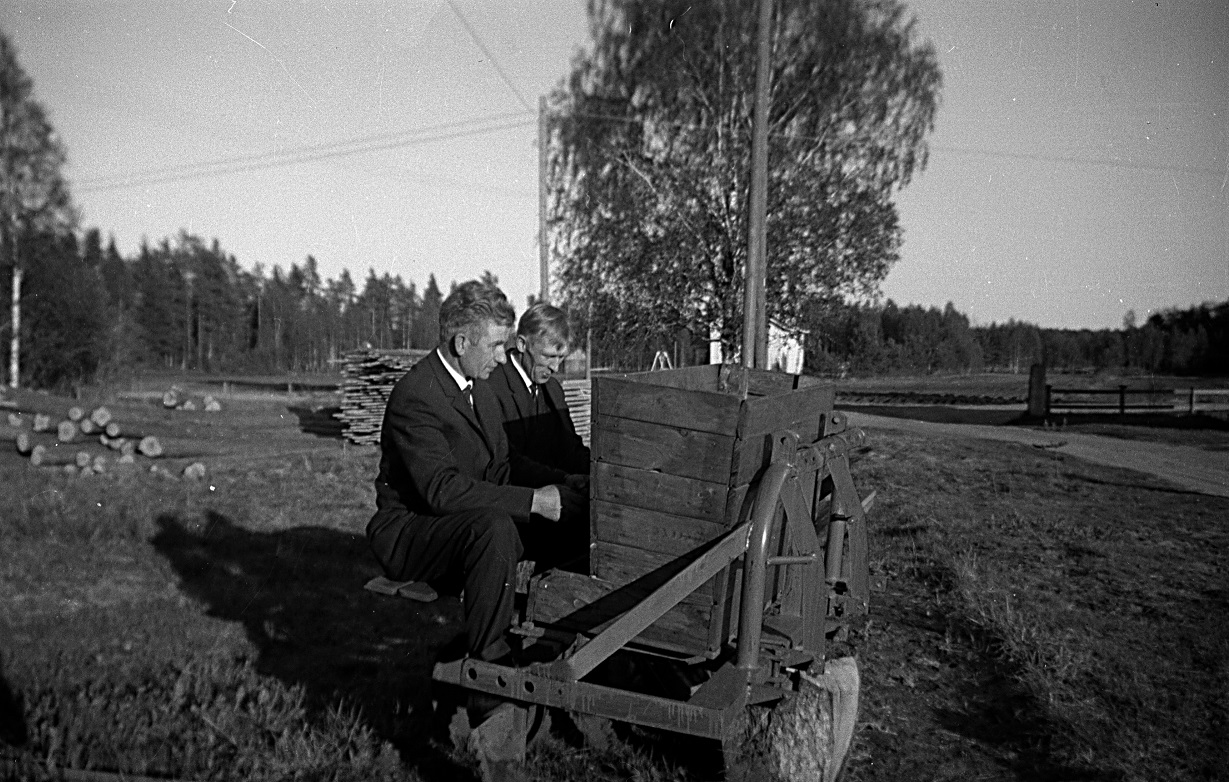 År 1964 skaffades en riktig potatissättare och här prositts den av Ragnar och svågern Per Rosenstedt från Perus. Stockarna t.v skulle Ragnar hyvla till pärtor. Huset bakom björken är Arvid Lillkulls.