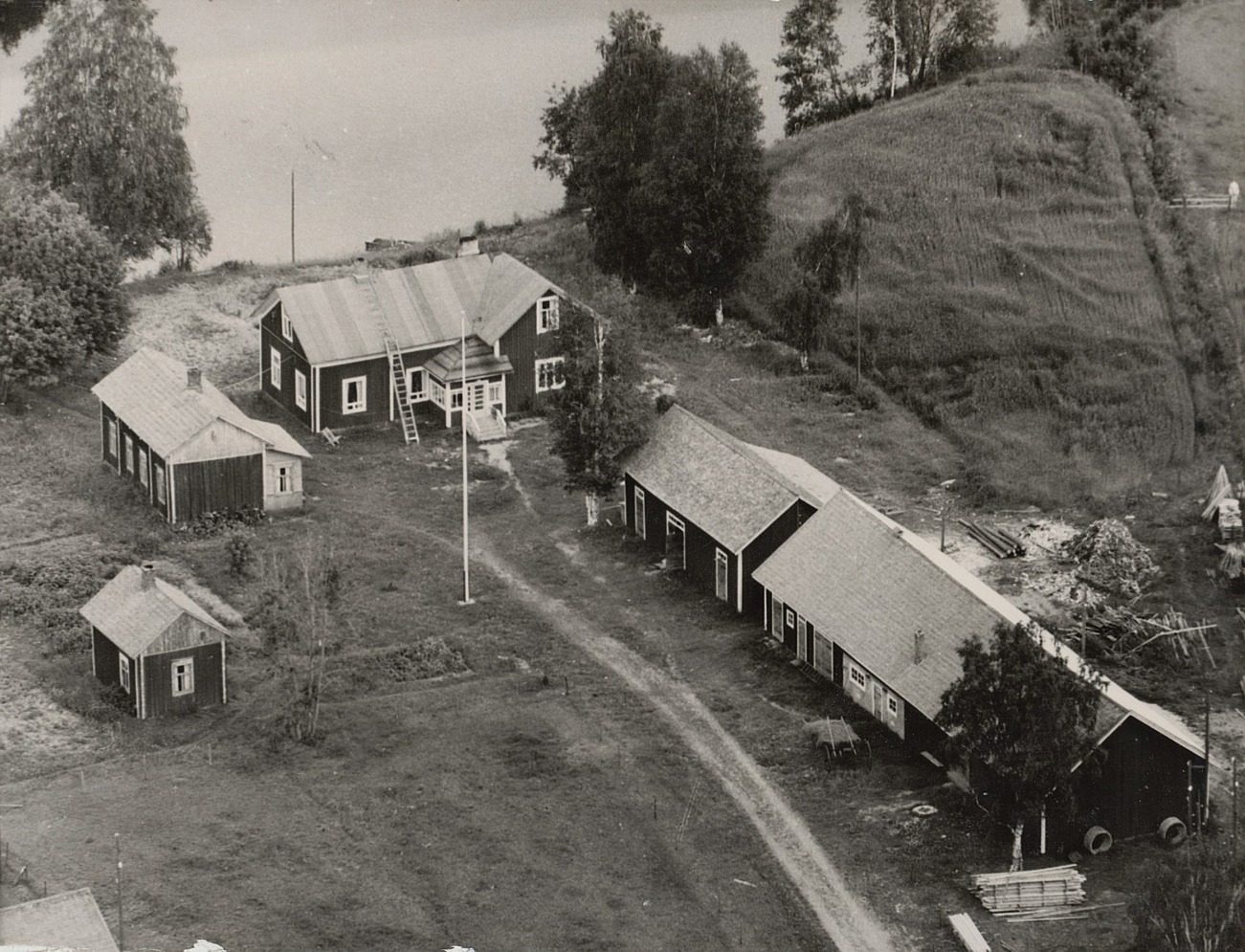 På den här flygbilden från 1960-talet så ser åkern bredvid gården ut som ett högt berg men i själva verket är det nog bara en vanlig, slät åkerplätt.