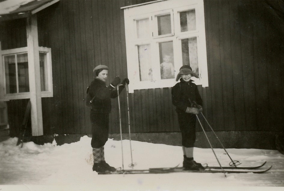 Vintertid förkortades vägen till skolan betydligt då det gick att skidande snedda över Klemets åkrarna. Per-Erik först och Henry Rosenback från Bergåsen, som var en duktig skidåkare kommer efter. Lillabror John tittar i fönstret.