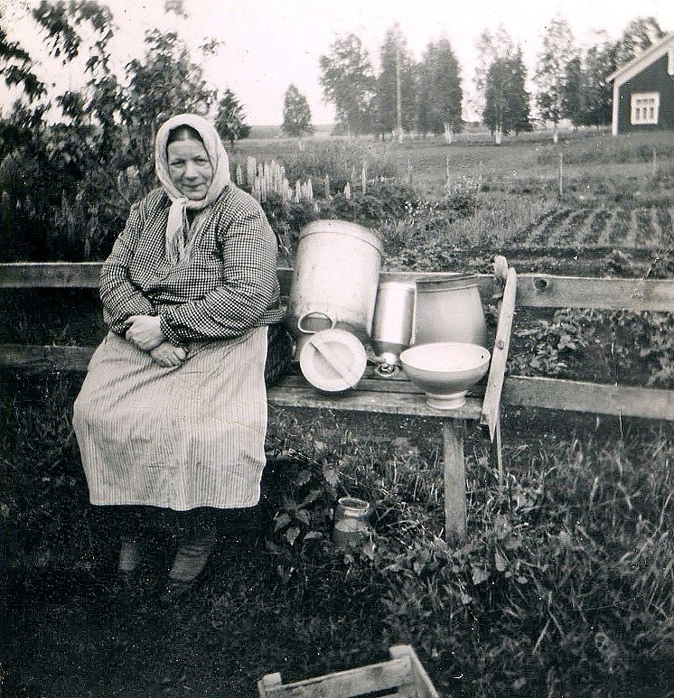 Hilma Sandbacka ser nöjd ut då mejarkannon, mjölkkannon, mjölkämbaret och mjölksilen är urtvättade. I bakgrunden syns litet av Valter Långfors gård.