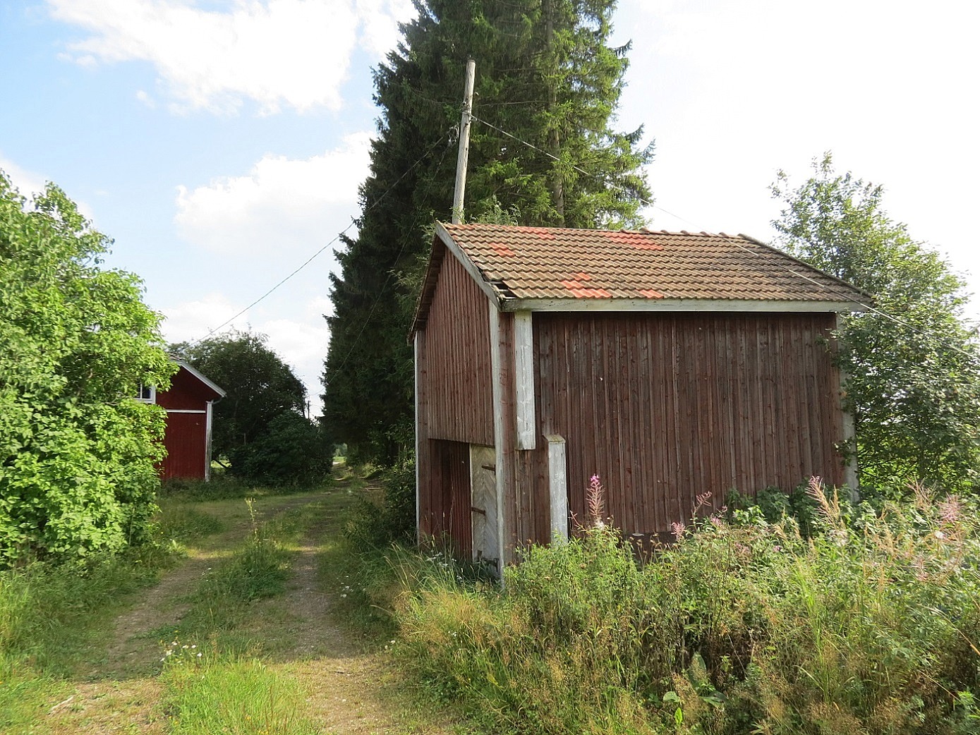 Detta gamla härbre stod tidigare nere i byin, men flyttades i samband med storskiftet år 1906 till en plats inne på gården. I slutet på 1930-talet rullades det iväg till denna plats, pöllien päällä. Pauli Hällback minns berätta hur förvånad han var en dag då han kom hem från skolan och märkte att härbret var flyttat. Johannes hade nog haft hjälp av någon av sina bröder med flyttningen. Huvudbyggnaden i bakgrunden, fotot 2014 taget från norr.