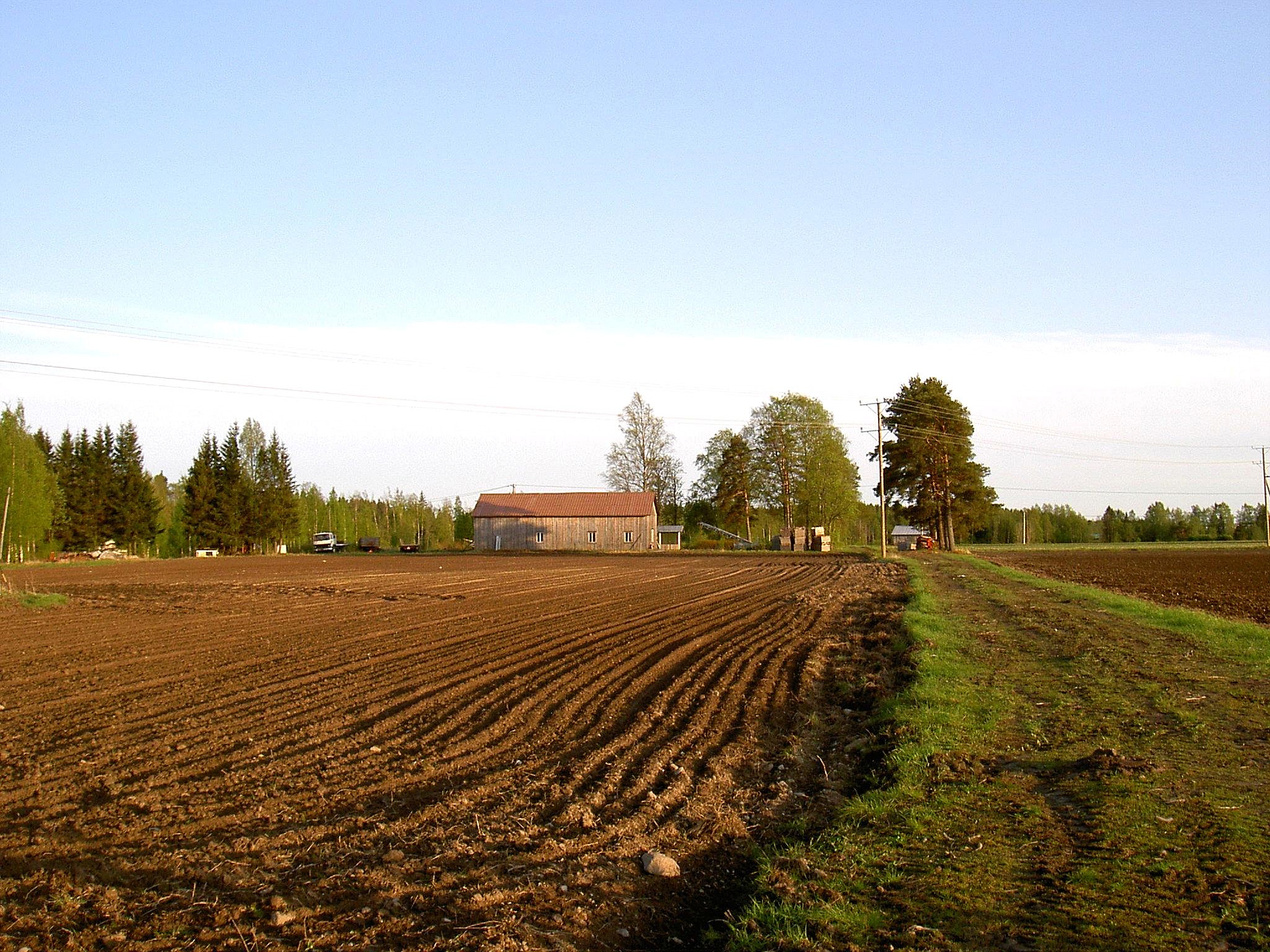 Mitt på fotot som är taget från Bötomhållet så ser vi det uthus som Torolf Lindfors byggde på 1980-talet. Det står på samma ställe som det uthus som Viktor Storkull byggde år 1927. Vägen som syns till höger är den gamla Åbackvägen men som i dag kallas för Nybond-tå. Den fortsatte i tiderna upp till Bötom men den togs ur bruk då den nya Åbackvägen byggdes färdig på 1930-talet. Hos Lindfors kallades denna sista vägstump för Rivägen eftersom deras ria låg utefter denna. 