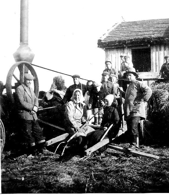 Så här kunde det se ut då det var tröskningstalko i Dagsmark. På bilden från ca 1940 står Johannes Hällback t.v. och lutar sig mot ångmaskinens remskiva som drog tröskverket. Mitt i bild sitter mor Hilma med sonen Pentti Hällback och längre bak står Penttis bröder. Mannen t.h. heter Paavilainen och han var hemma från Alakylä i Bötom. Fotot är taget bakom den stora ladan som står och lutar på den övre bilden. Det här tröskverket och ångmaskinen hade Johannes i bolag med Valdemar Rosengren köpt av ett tröskandelslag nere i Dagsmark. I Kauhajoki gjordes ångmaskinen om och på skorstenen byggdes ett gnistskydd som syns i nedre delen av skorstenen. Men när de fick 3-fas elektricitet till Åbackan anskaffades en Strömberg elmotor och ett riktigt Sampo Rosenlew tröskverk. Efter en tid löste Johannes ut Valdemar ur andelslaget och tröskverket och elmotorn finns ännu i behåll hos Hällbacks. 