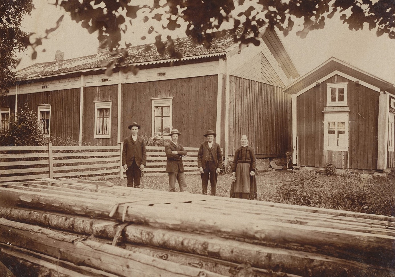 Så här såg Koll-gården på Kårkbackan ut år 1908 fotograferad från väster av Viktor Nylund. På fotot Viktors bröder byggmästaren Emil Storkull och den blivande bonden Erik Anders som år 1910 bytte namn till Englund. Till höger husbonden ”Koll-Josip” och hans Anagret. Virket i förgrunden skulle användas på det nya stället i Palon.