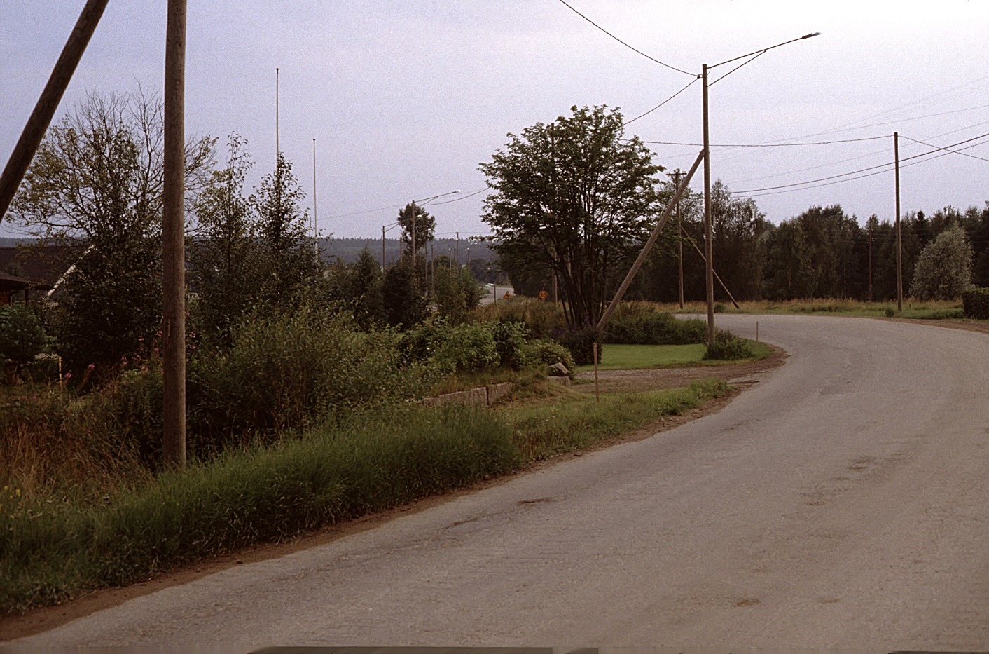 Landsvägen från Sebbas-backan söderut år 1983. Taket t.v. är på Kurt Backlunds gård och stenfoten som syns mitt i bild hörde till Noréns affärshus. 