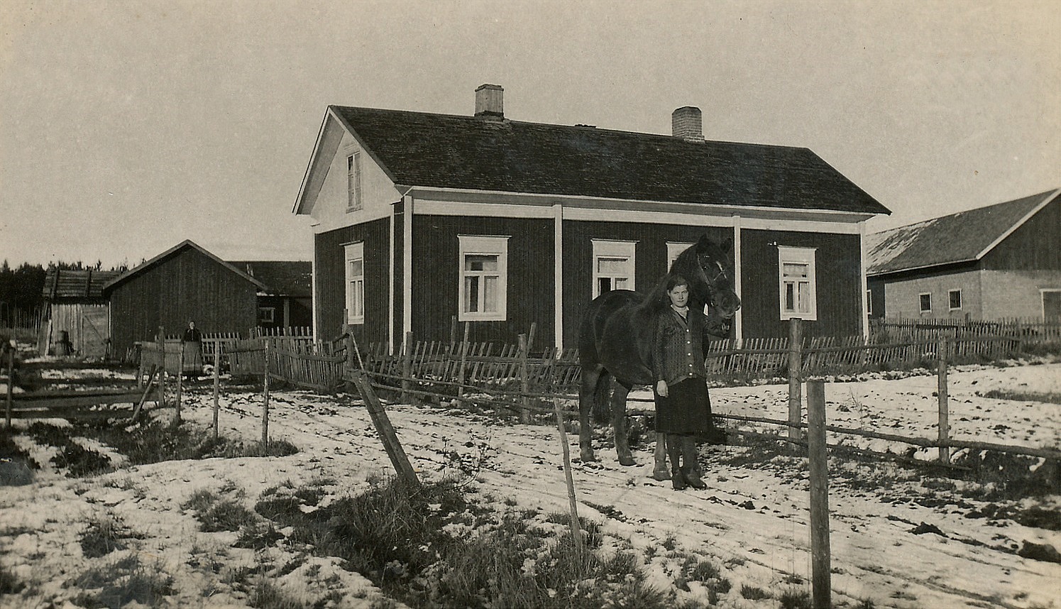 Så här såg Åsinas-Viktors gård ut i slutet på 1930-talet. I grinden står Viktors hustru Edla Maria (1869-1941) och ser på fröken Elin Rosenback är på väg ner mot Åbackvägen med hästen. Foto: Artur Lövholm.