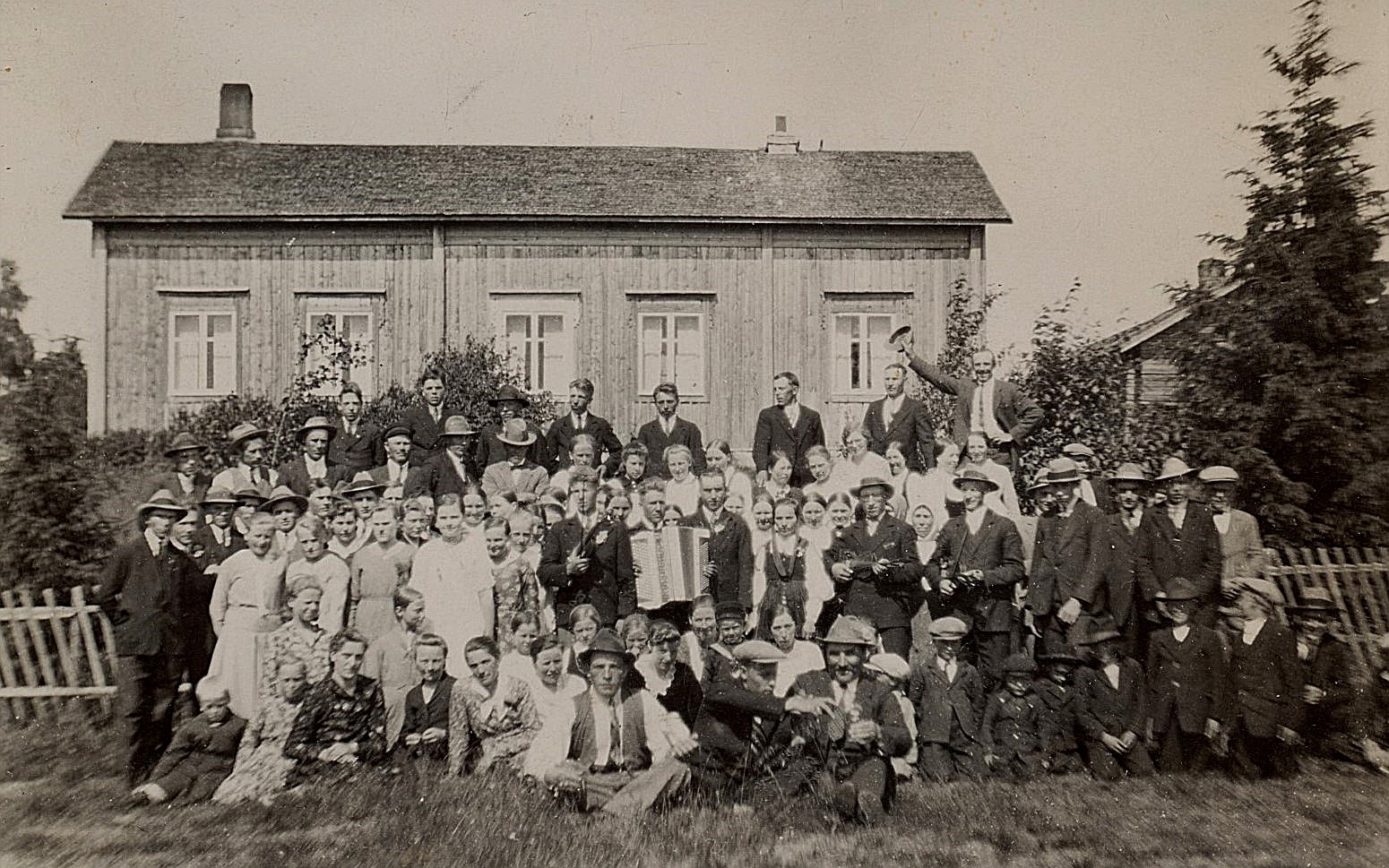 Det är svårt att urskilja brudparet Hulda Nyholm och Emil Hammarberg bland alla glada bröllopsgäster åt 1931. Nyholms gård i bakgrunden.