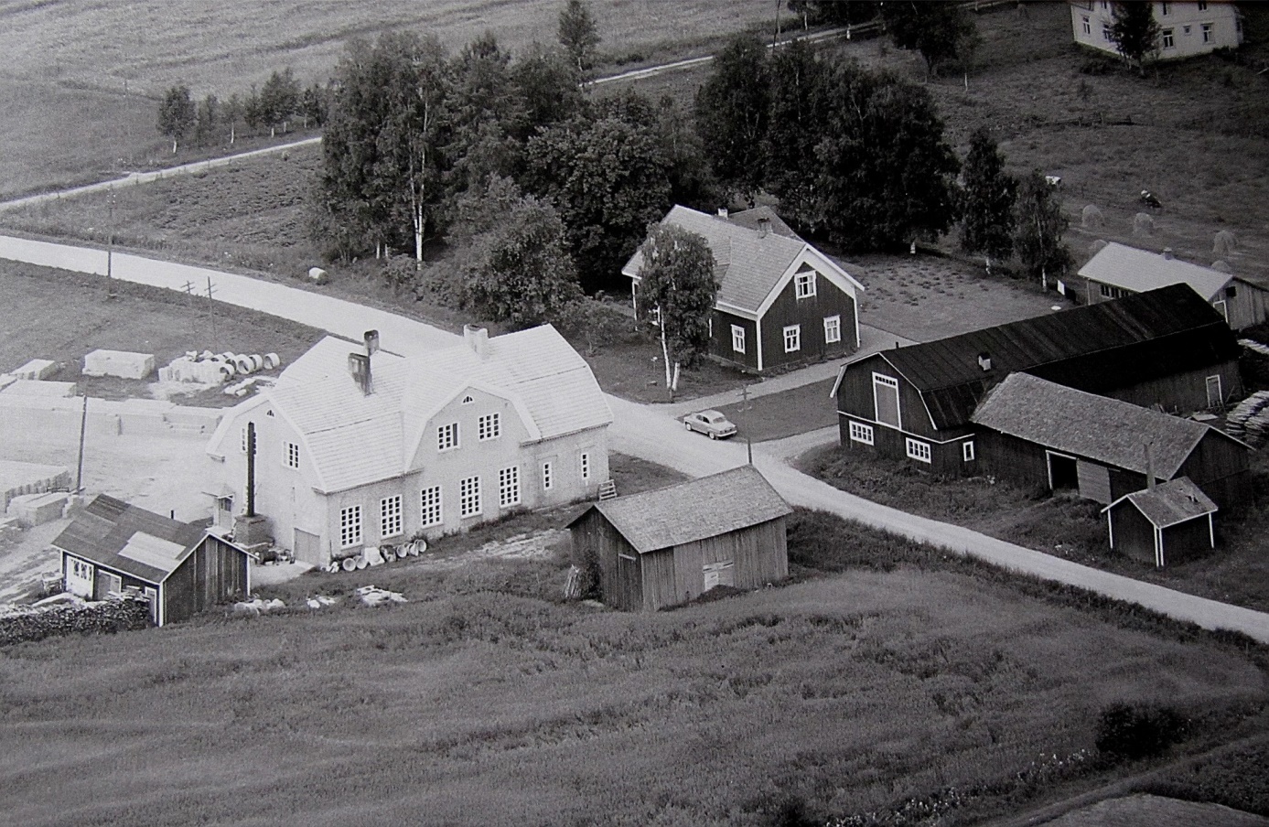 Den stora tegelbyggnaden till vänster är Dagsmark Andelsmejeris byggnad från 1929 men som när detta foto togs 1961 ägdes av Ragnar och Verna Långfors. De bodde i övre våningen och i bottenvåningen tillverkade de tellblock av cement. Mejeribyggnaden förstördes i en brand sommaren 1977. På andra sidan Åbackvägen står Krook-gården som just detta år övertogs av Boris och Gun-Lis Långfors. Den stora uthusbyggnaden med mansardtak förstördes i en brand sommaren 1966 och efter det byggdes de uthus som fortfarande står kvar. Uppe i högra hörnet syns lite av Storkulls gård.