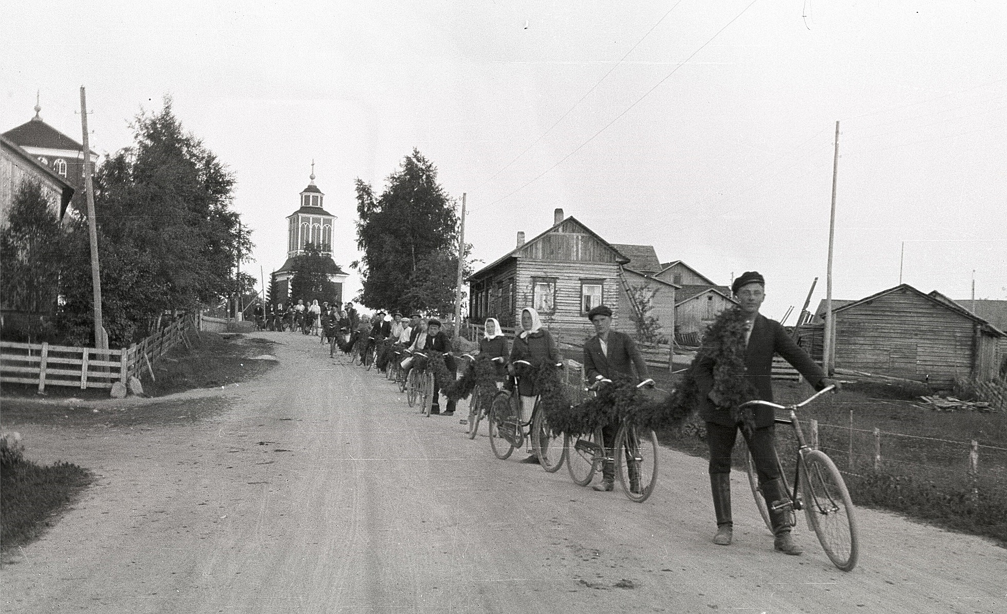 Den här långa enriskransen som körs nedför Svedarbacken skall användas vid den stora sångfesten som ordnades vid ungdomslokalen 1930. Den skall dekorera estraden och ingångsporten, längst fram Hemming Ådjers, Emil Björknäs, Hjördis Ingves.