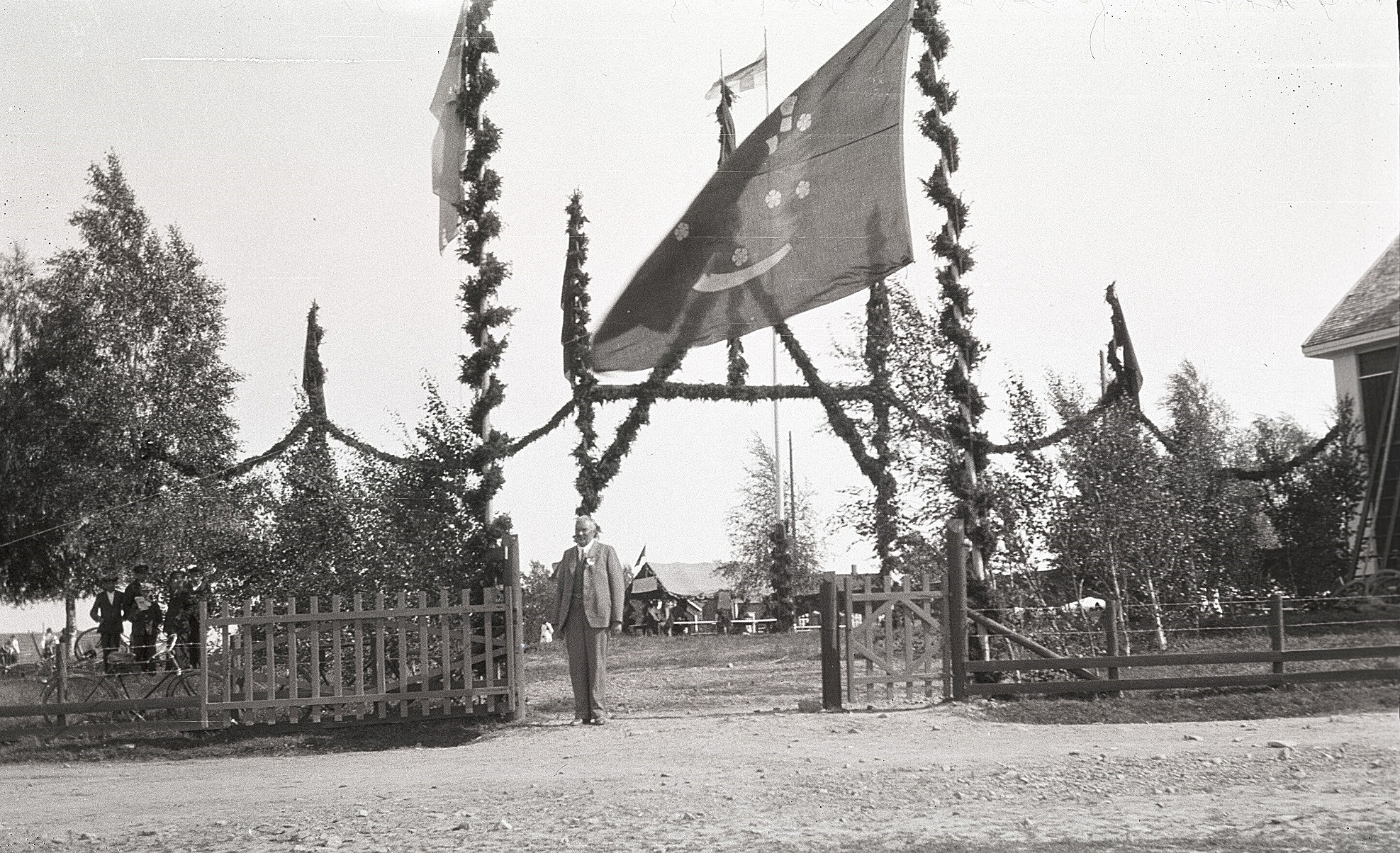 Den ståtliga porten till idrottsplanen under sångarfesten i Lappfjärd 1930. Gaveln till lokalen syns i högra kanten.