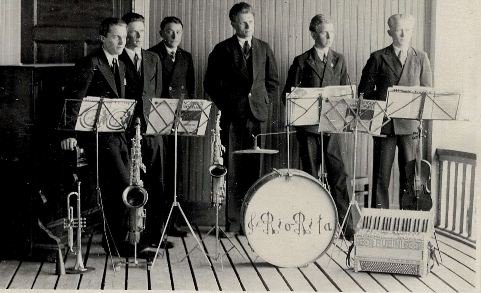 Mellan åren 1932 till 1939 så var Rio-Rita den absolut populäraste dansorkestern i Syd-Österbotten. Från vänster Åke Knus, som spelade piano, Emil Björknäs på tenorsaxofon, Birger Lillhannus på trumpet, Lennart Knus på altsaxofon, Elis Knus på dragspel och Otto Fröberg på fiol och dom står på lokalens uteveranda i Lappfjärd. Från början hade orkestern också flera andra medlemmar, bland annat Valter Enlund, Torsten Pärus, Sigurd Brogård, Valter Brogård och Egil Appel.