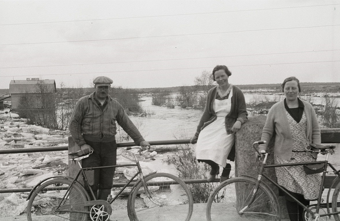 Här står Emil Ekman, Ines Hannus och Signe Nyqvist på Nybron och tittar på islossningen. Cykeln till höger tillhörde troligtvis fotografen, för knappast skulle damerna ha klarat av att köra med "karavagne" med de där kläderna.