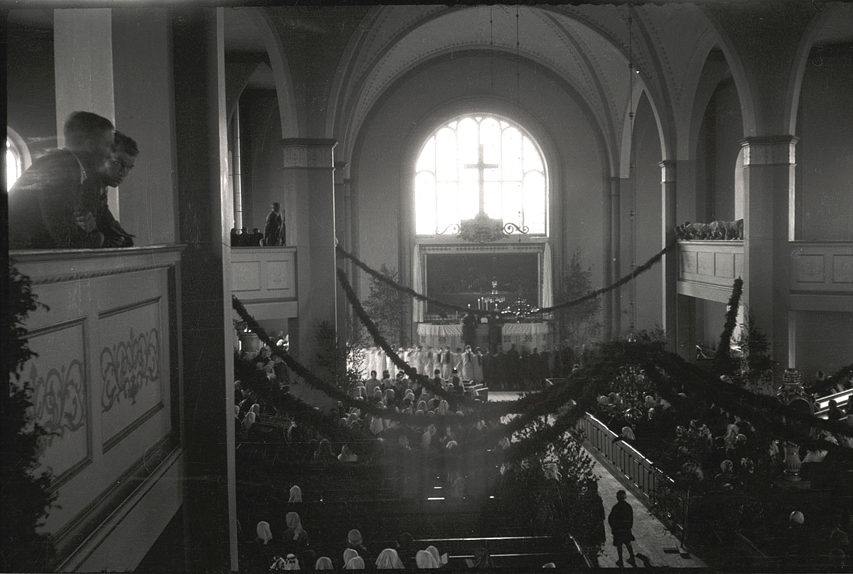 Midsommardagen 1931 var kyrkan dekorerad med björkar och enrisband. Konfirmanderna står i flera rader runt altarrundeln.