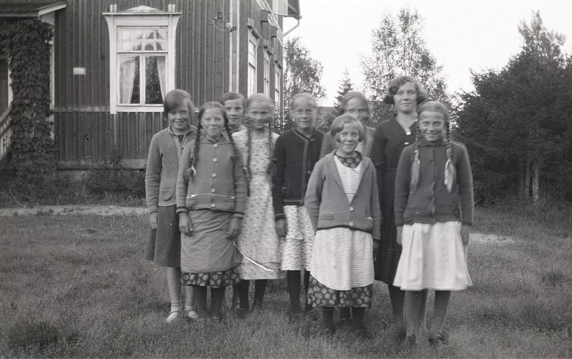 Dagsmarkflickor utanför folkskolan, från vänster Lilli Eklund, Helga Englund, Else Rosenback, Edit Agnäs, Ingeborg Krook, Anna Englund, okänd, Lilja Nordberg och Ellen Westerback.