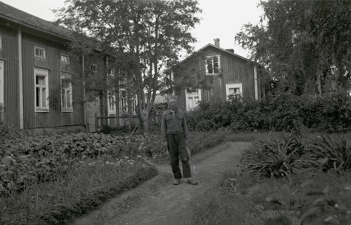 Birger Hellman står utanför hemgården, mitt bland blommor och lök.