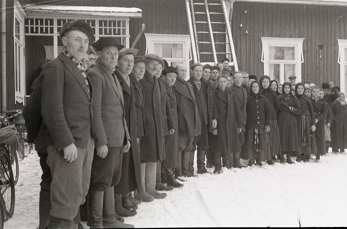 Veteranerna från frihetskriget 1918 eller deras anhöriga står här på rad utanför södra skolan, vid utdelningen av förnödenheter.