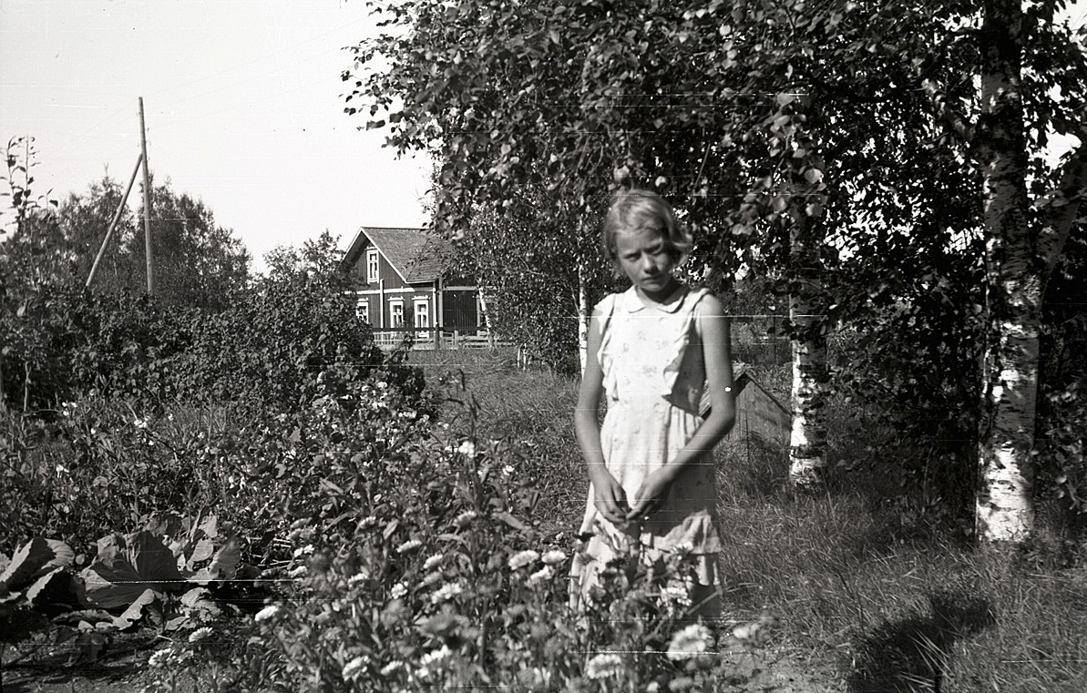 Karin Knus, som sedan gifte sig med Michael Mangs från Tjöck. I bakgrunden Emil Knuts gård.