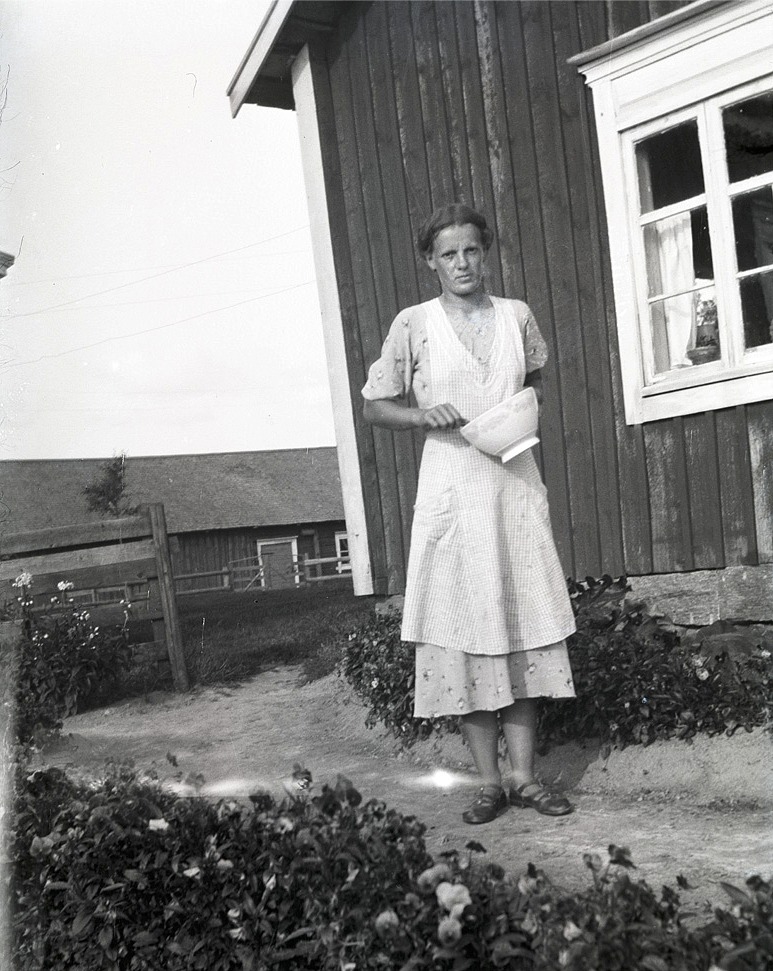 Anni Enlund som följande år skulle gifta sig med Birger Holm står här och vispar till en kaka bland blommor och blad.