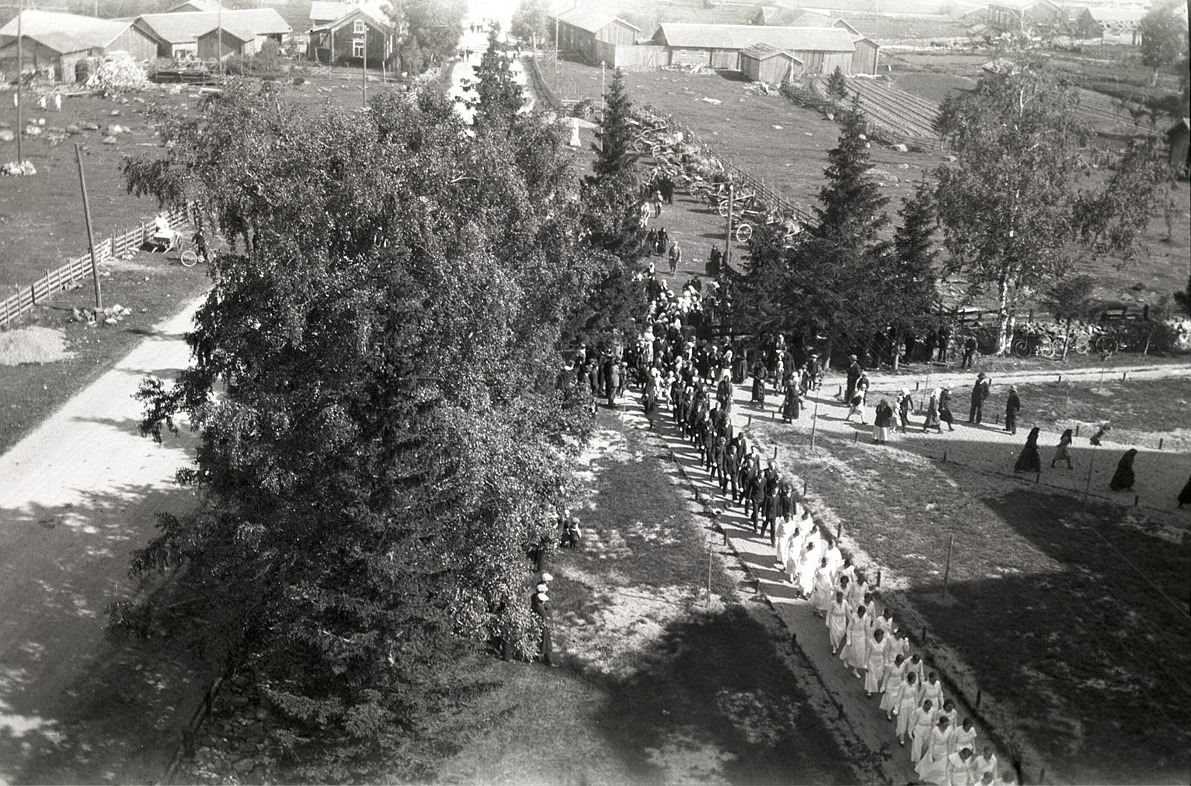 Lång rad med konfirmander på väg in i kyrkan midsommardagen 1939.