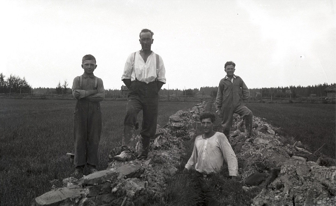 Till vänster Helge Holm (1927-2017) bredvid pappa Erland (1896-1950)och till höger står Olof Holm (f. 1925) och ser på då en okänd man håller på och täckdikar i åkern.
