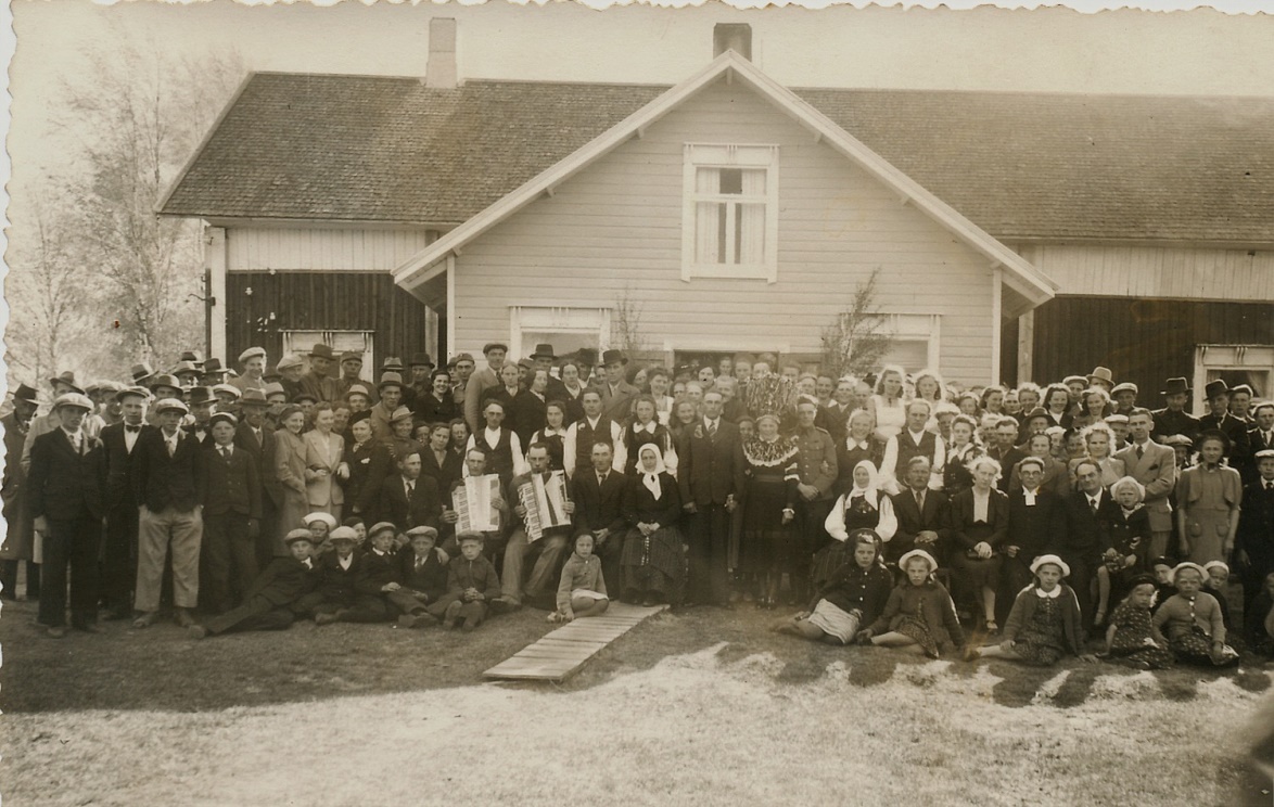 Gunnar och Svea Norrgård omgiven av släktingar och övriga bröllopsgäster framför Sveas hemgård i juni 1941.