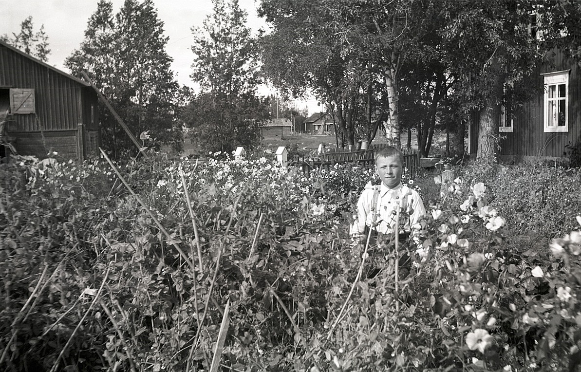 Bland blommorna står Lars Börje Engelholm. Till vänster syns pappa Arnes kvarn.
