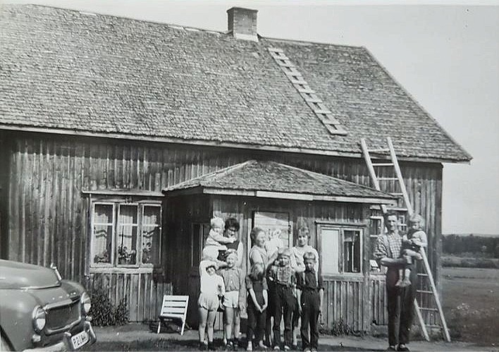 På fotot från mitten på 60-talet står Elisabeth Dahlroos, senare Svensson med dottern Helena i famnen. Fram henne står de andra barnen Gunilla och Magnus. Mitt i bild står Sylvia med Lasse i famnen och framför står Carola, Ole och Elof. Till höger Otto med Saga i famnen.