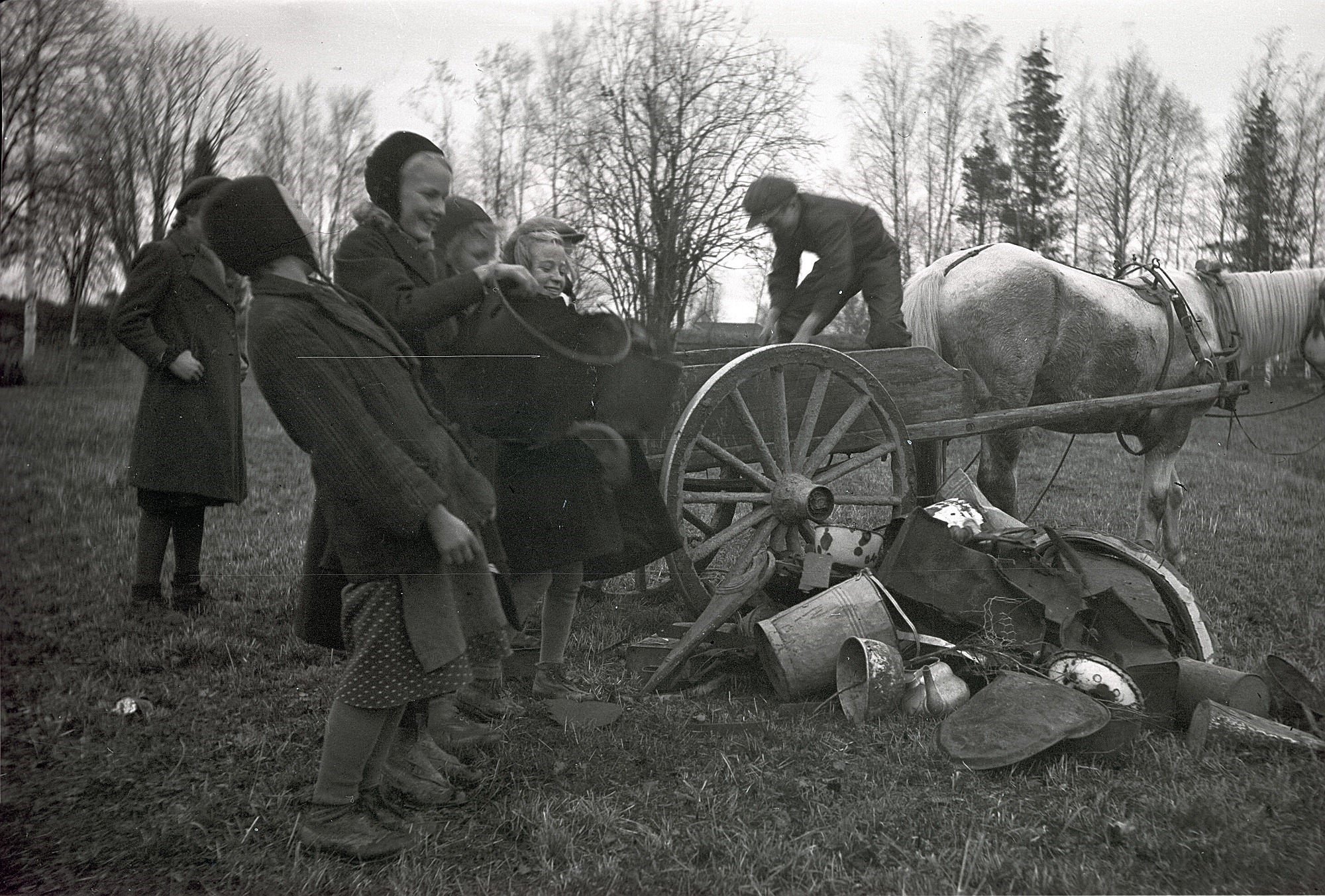 Under krigsåren 1941-44 samlade skolbarnen skrot för försvarsmakten. Pojken på kärran lastar av de insamlade metallerna medan flickorna ser på. Från vänster Etel Storsjö, Elvi Lassfolk, Ulla Sjöberg, okänd och Astrid Nissander.