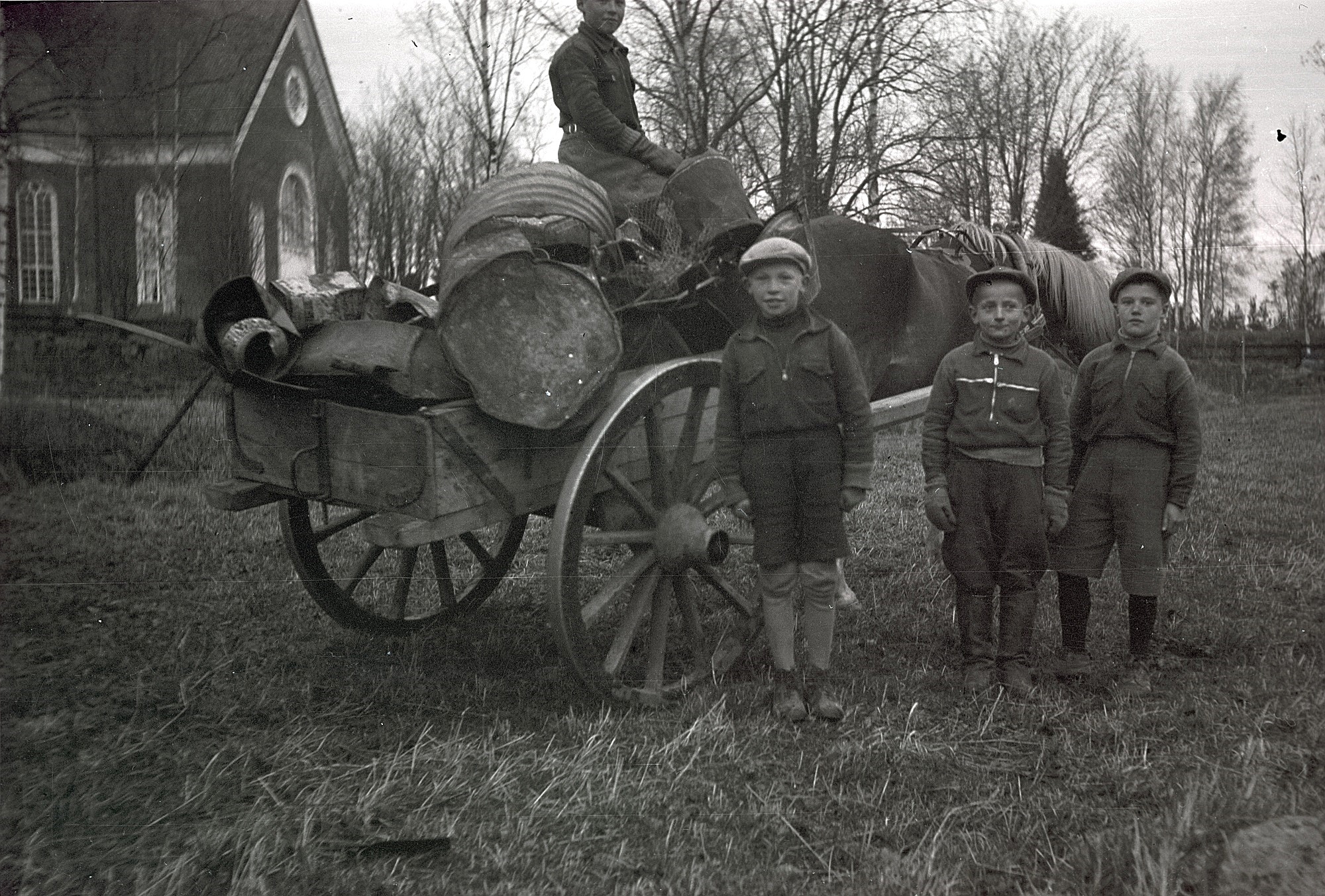 Under krigsåren samlades gummi, glas och metallskrot och här står 3 stolta pojkar som med häst levererar de insamlade metallerna. Från vänster Bengt Engelholm, Harald Marttila och Mikael Björses. Personen på kärran är oidentifierad.