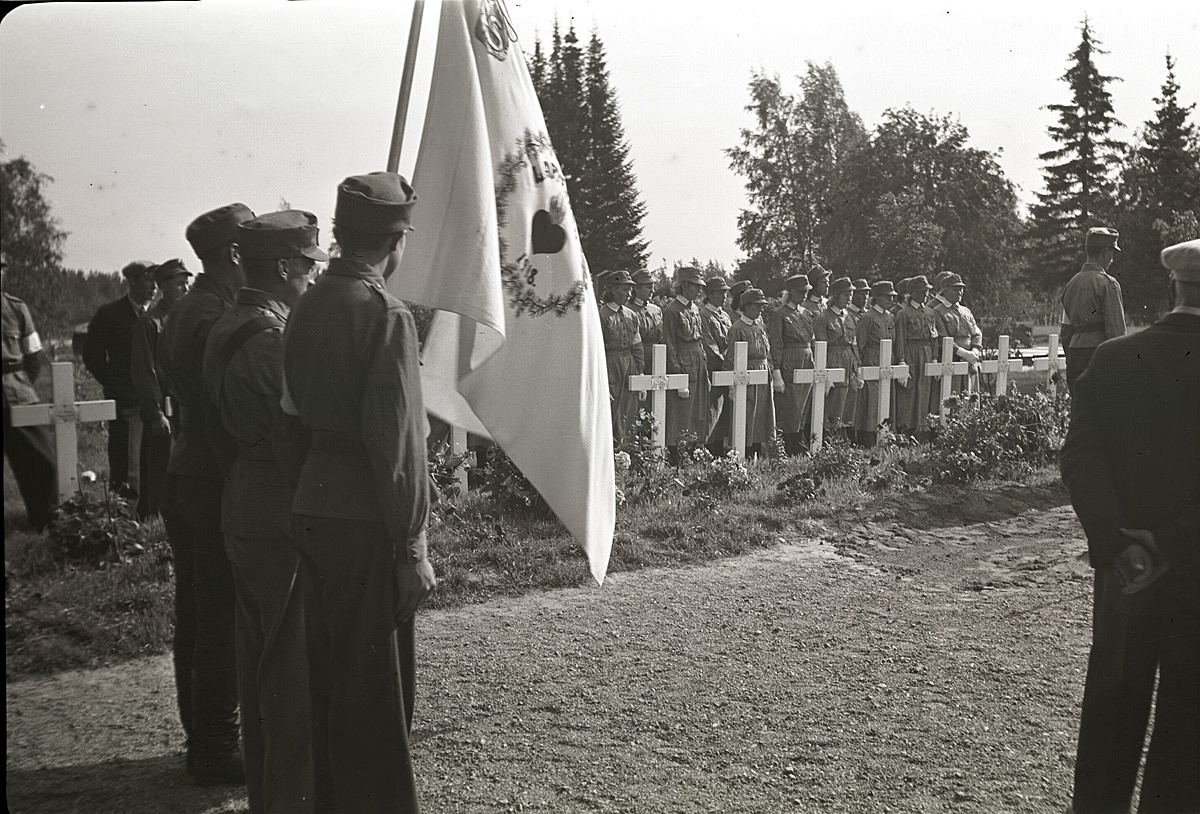 Skyddskårens fana vajar då Eskil Ålgars begravs på begravningsplatsen bredvid kyrkan i Lappfjärd.
