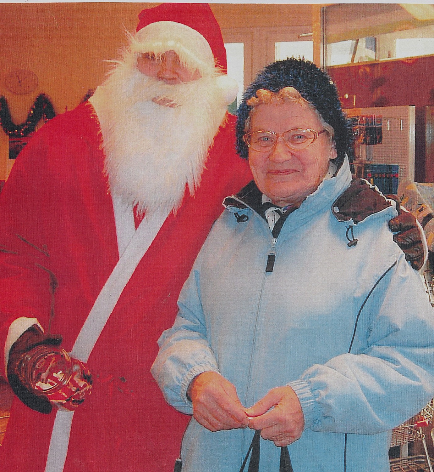 Helvi Klemets ser nöjd ut då jultomten kramar om henne i bybutiken i Dagsmark