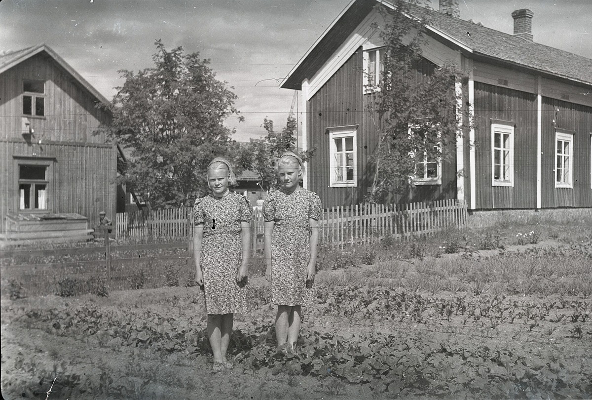 Systrarna Irma och Margit Rosendahl i trädgårdslandet framför hemgården i Lappfjärd.