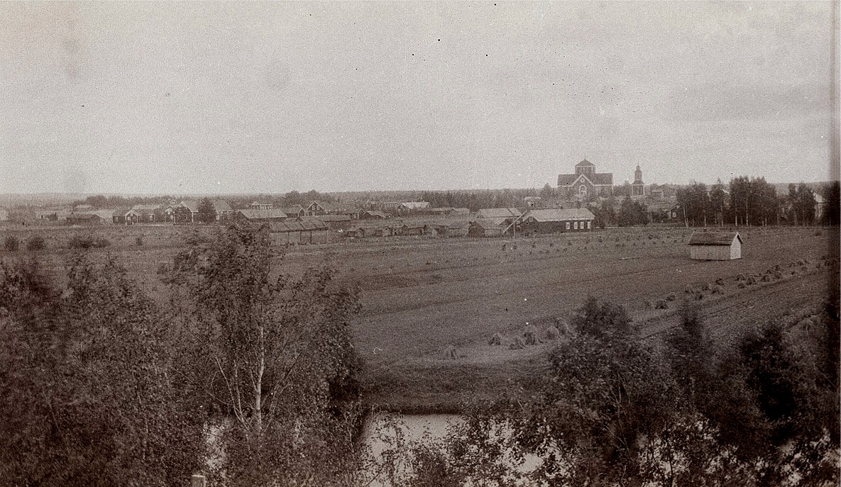 Fotografi taget från norra sidan mot kyrkan. Framför kyrkan Lillmangs gård med de 4 fönstren och till höger