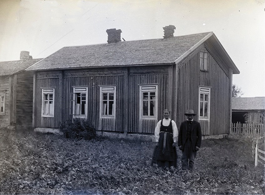 Här står Klemets Emil och Manda framför gården medan den ännu stod uppe i centrum lite öster om folkskolan. Fotot från ca 1915 och gården flyttades sedan ner till Klemetsändan där den skarvades i med en vinkel.
