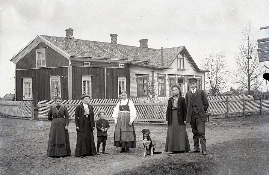 Fina gäster uppställda utanför Nylunds gård på Sunnantillvägen. Ida klädd i folkdräkt med lilla Rurik bredvid sig.
