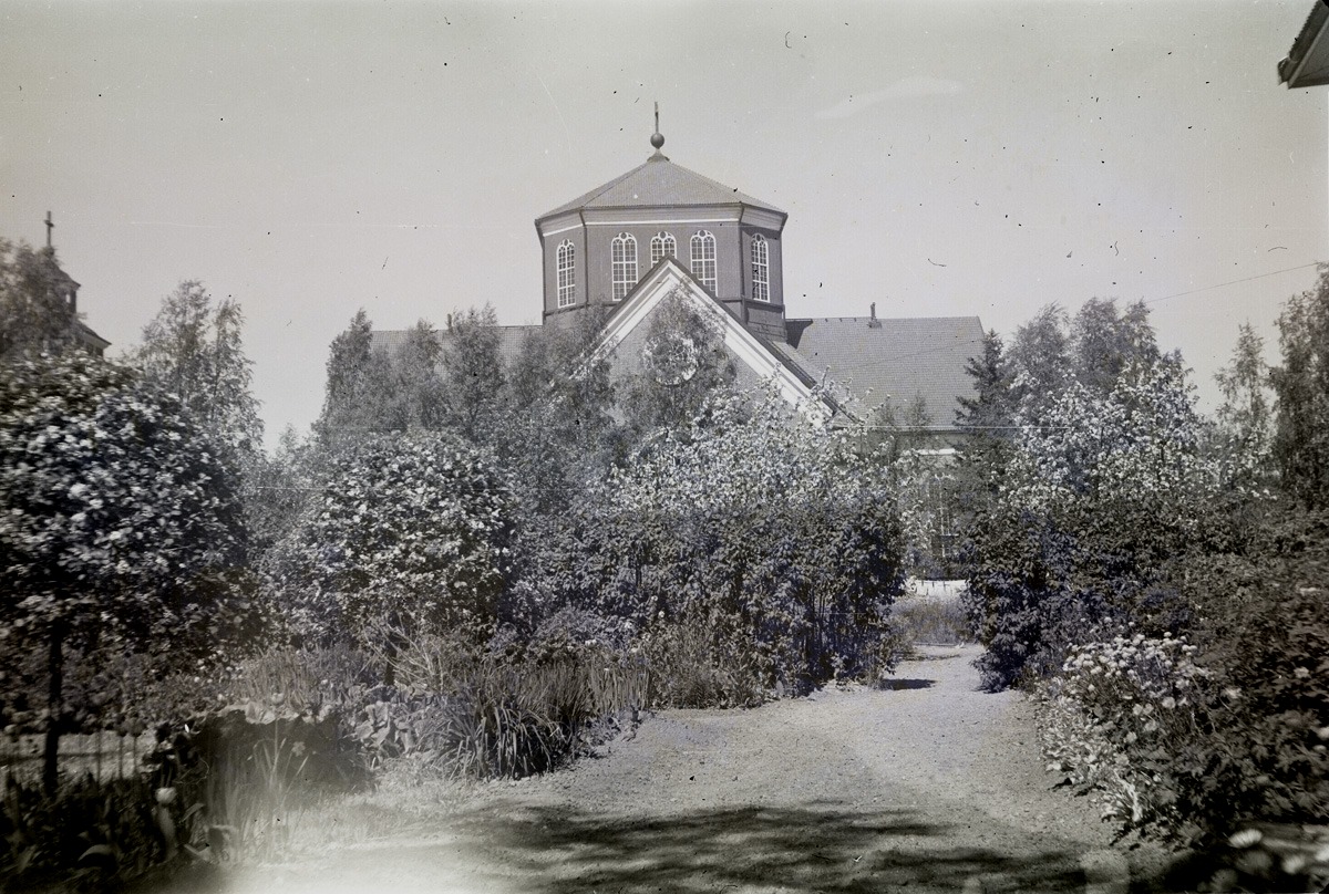 Så gott som varje år fotograferade Selim Björses sin trädgård vid södra folkskolan och här lyckades han få ett fint foto av kyrkan också.