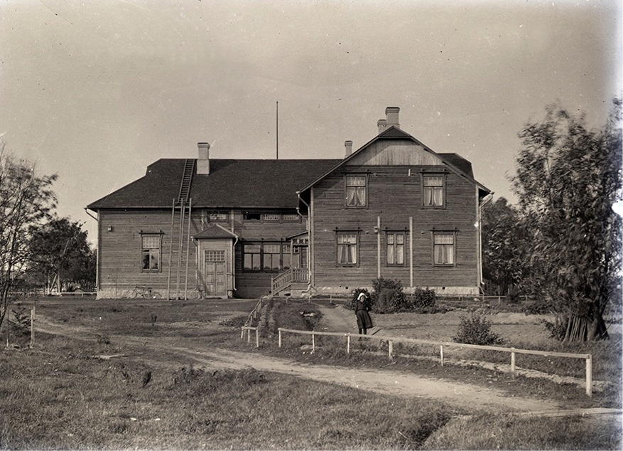 Lärarfamiljens privata trädgård framför bostaden ingärdad med ett enkelt staket.