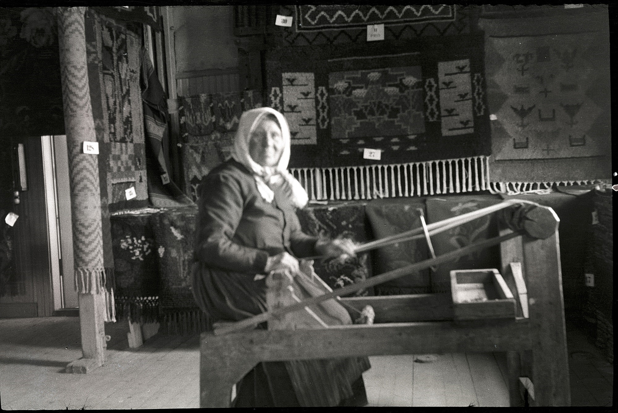Bleckslagar-Manda visar hur det går till att väva förklädesband på lantbruksutställningen i Lappfjärd 1938. Runt omkring henne finns flera fina vävnader utställda. Foto Selim Björses, SLS:s arkiv.