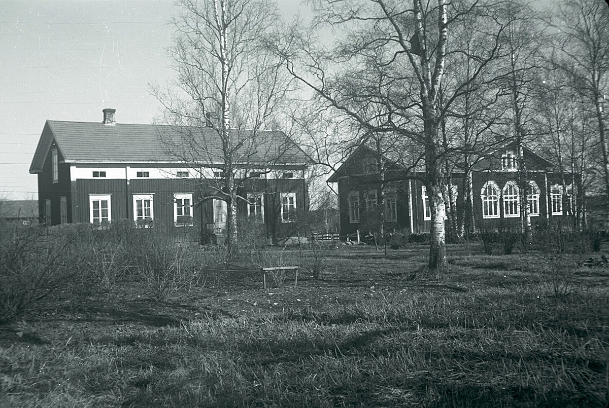 Till vänster lärarbostaden, som år 1879 byggdes till Lappfjärds bys första folkskola. När den nya skolbyggnaden till höger byggdes 1893, så renoverades den gamla skolan till två bostäder. Den ena var ämnad åt läraren och den andra skulle den kommande lärarinnan kunna bo i.