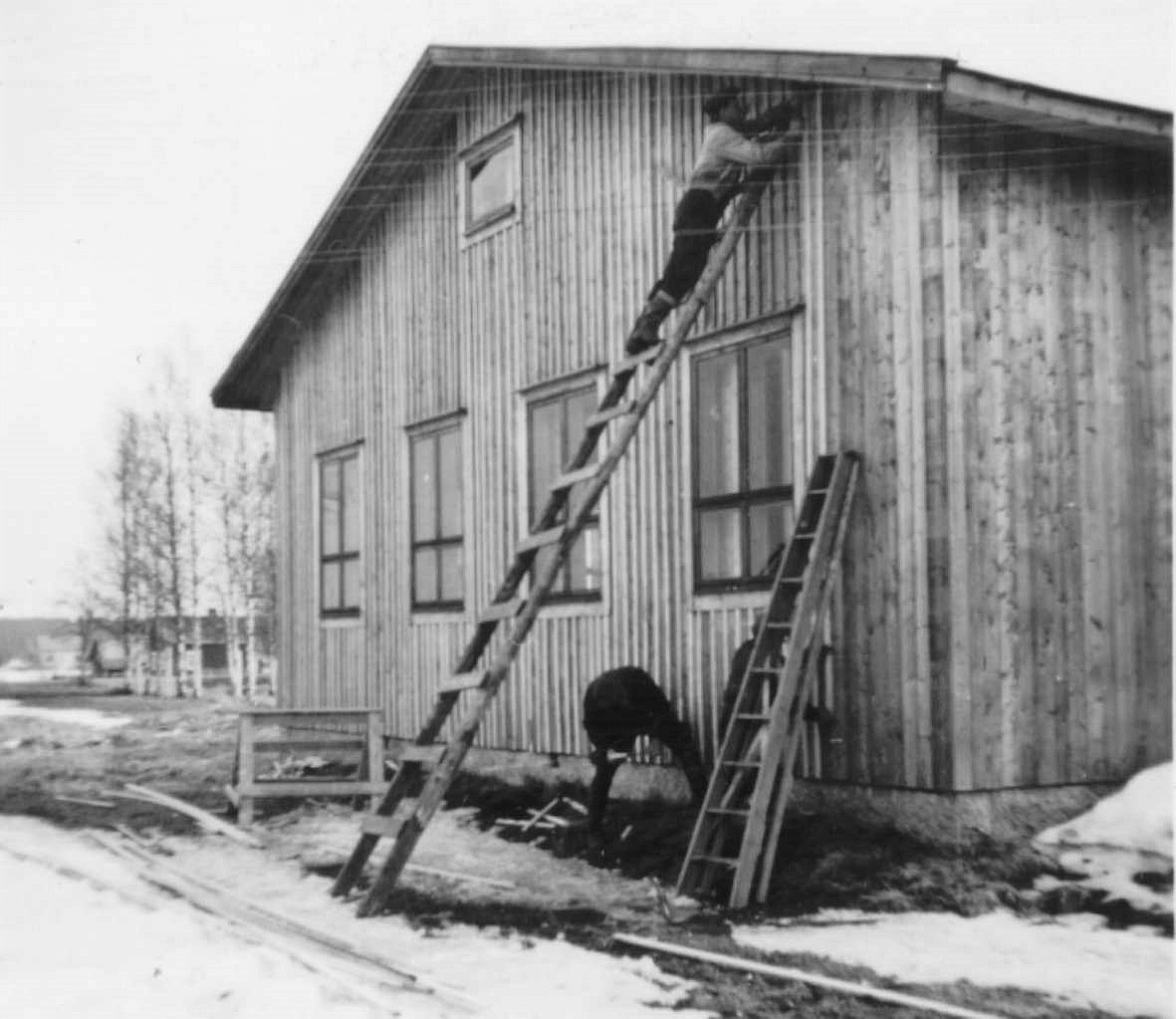 Gaveln till serveringsrummet "ribbas" , alltså ribbor spikas ovanpå brädfodringen. Klemets Erik Anders gård syns till vänster och riktigt långt bort står Åke Backlunds gård på A-sidon.